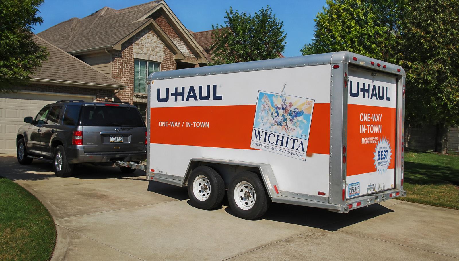 U-Haul enclosed cargo trailer hitched to an SUV in a suburban driveway
